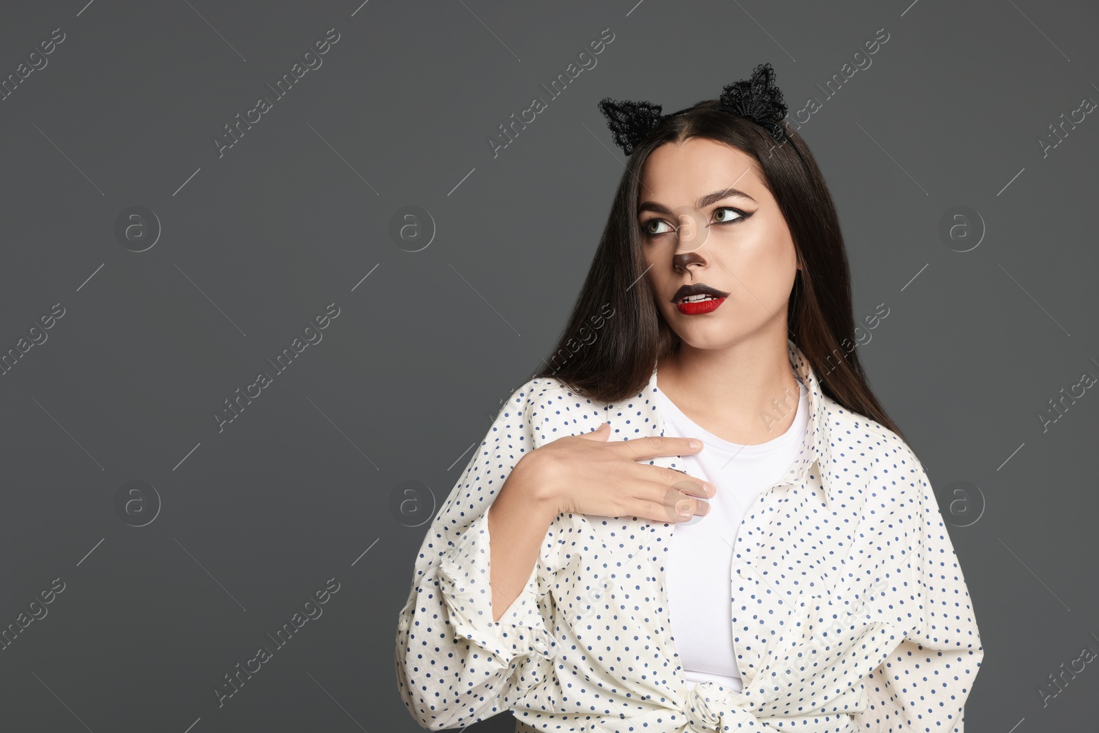 Photo of Attractive woman with cat makeup and ears on grey background. Space for text