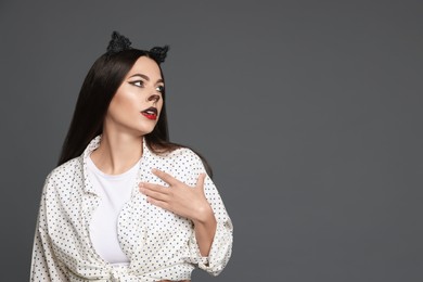 Photo of Attractive woman with cat makeup and ears on grey background. Space for text