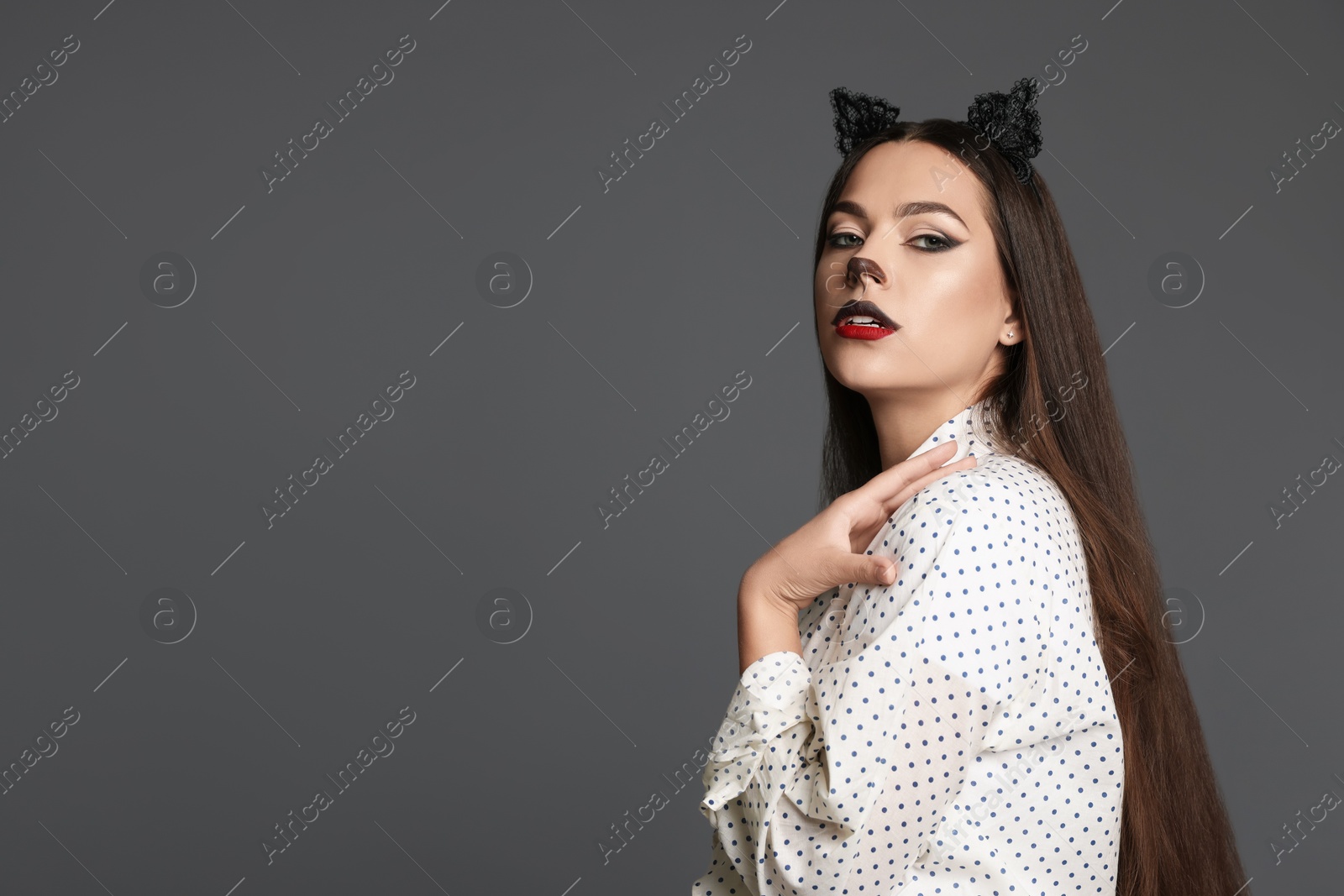 Photo of Attractive woman with cat makeup and ears on grey background. Space for text