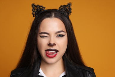 Photo of Woman with cat makeup and ears on orange background