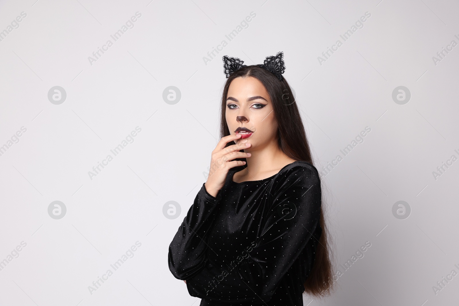 Photo of Attractive woman with cat makeup and ears on white background