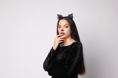 Photo of Attractive woman with cat makeup and ears on white background