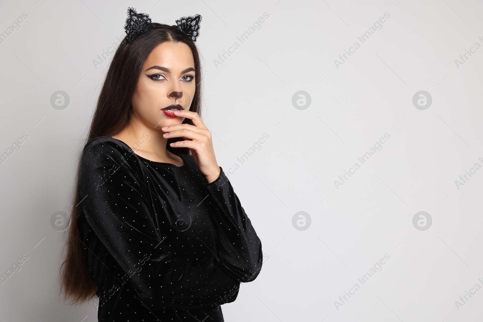 Photo of Attractive woman with cat makeup and ears on white background. Space for text