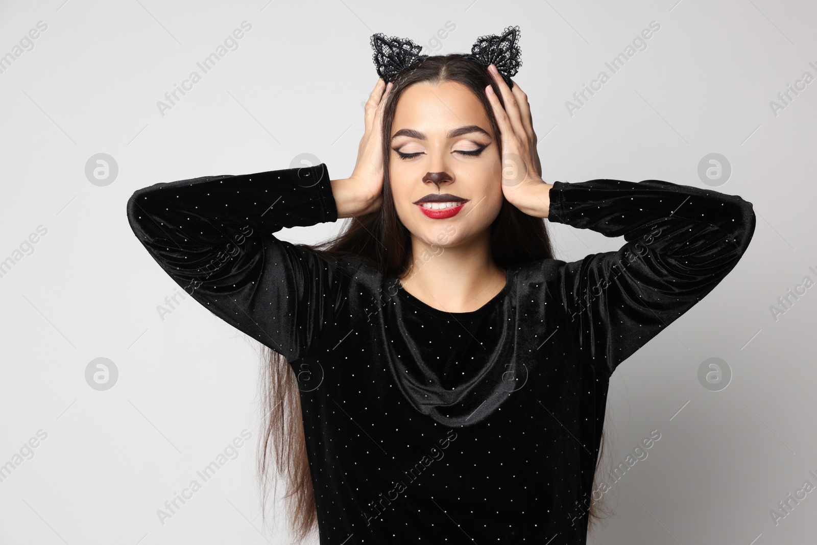 Photo of Smiling woman with cat makeup and ears on white background