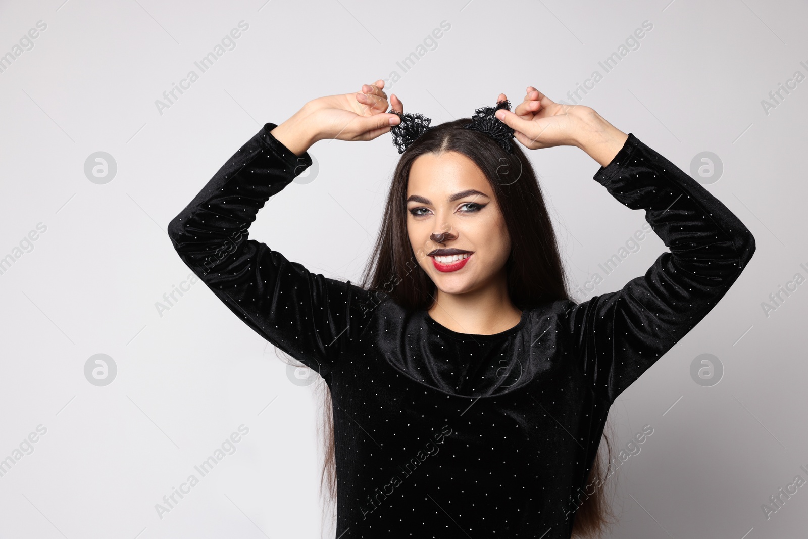 Photo of Smiling woman with cat makeup and ears on white background