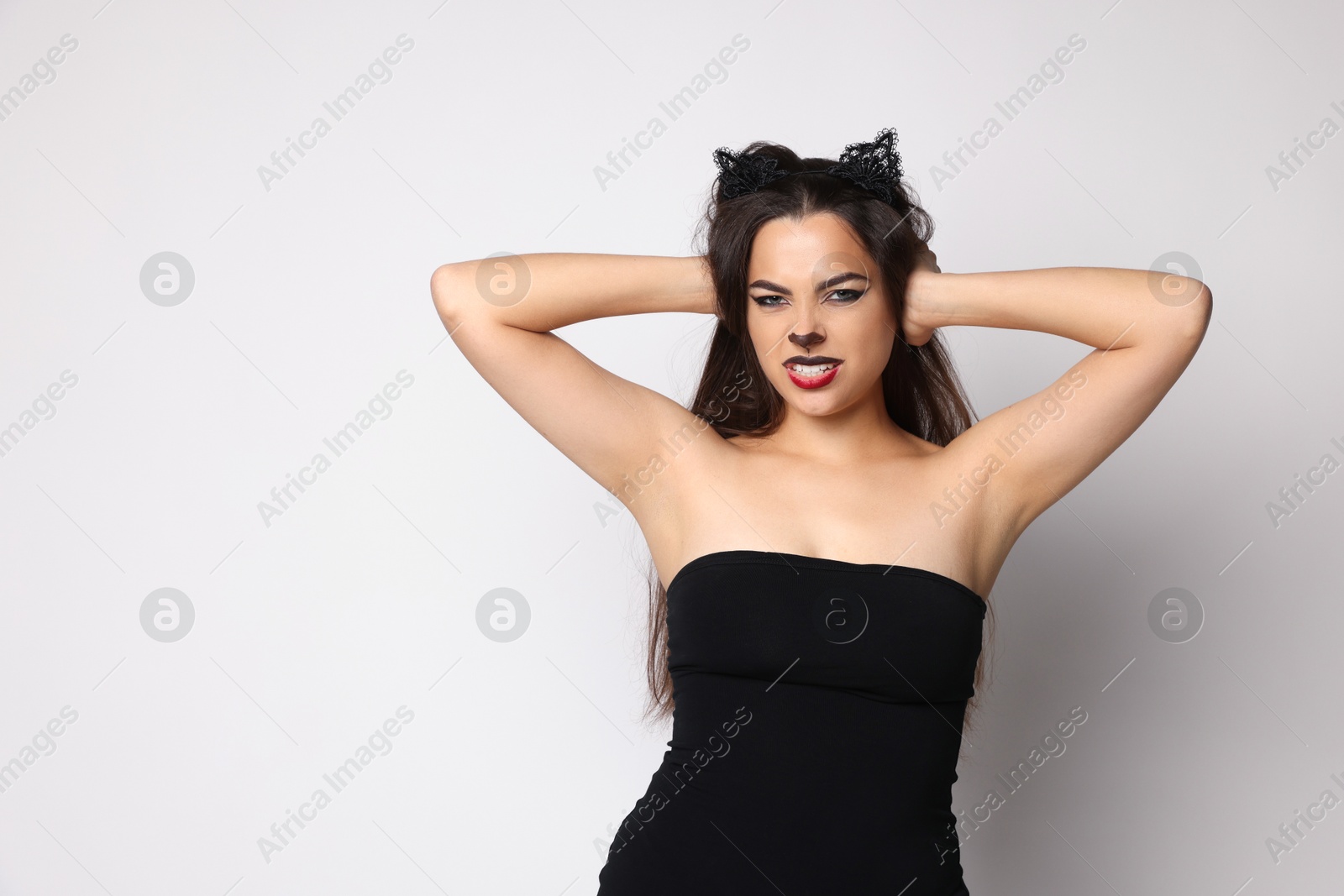 Photo of Smiling woman with cat makeup and ears on white background