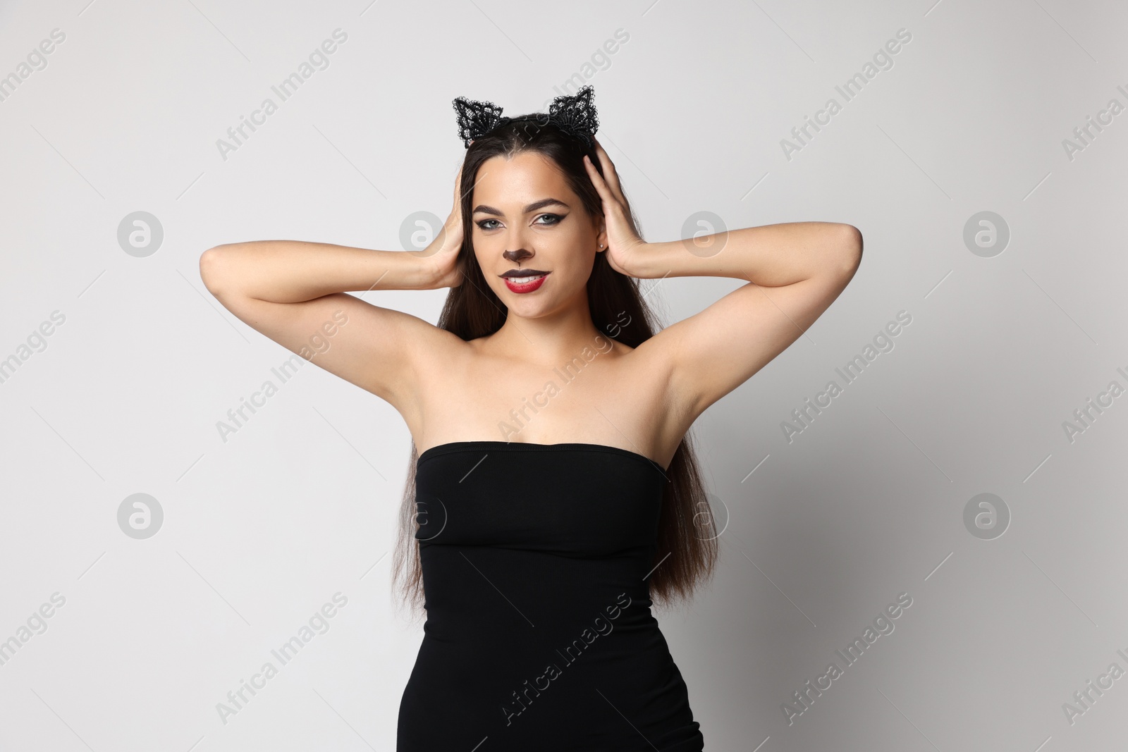 Photo of Smiling woman with cat makeup and ears on white background