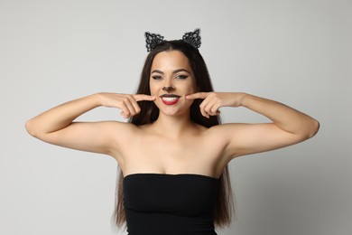 Photo of Smiling woman with cat makeup and ears on white background