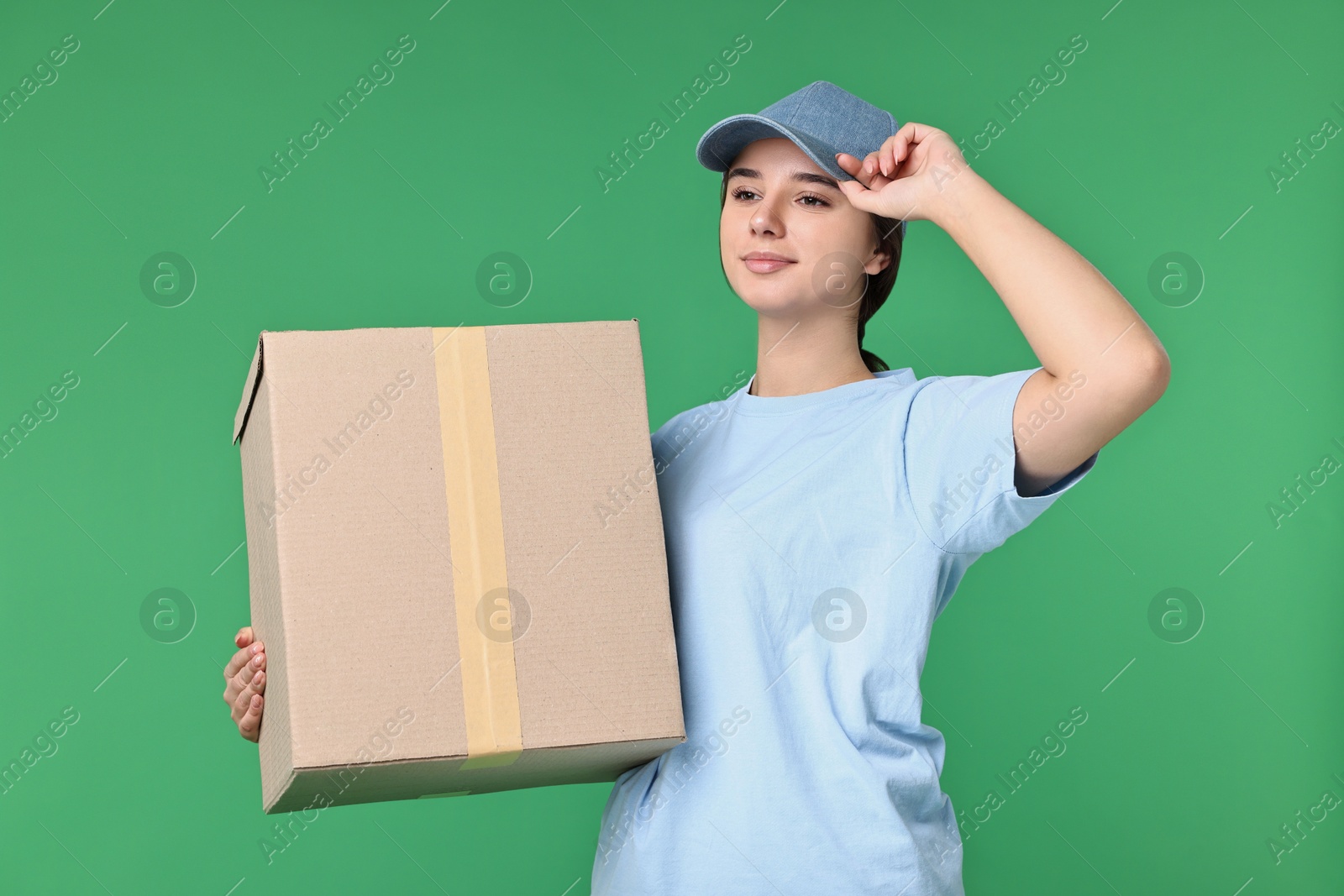 Photo of Girl in uniform with parcel on green background. Work for teenagers