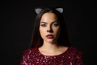 Photo of Charming woman with cat makeup and ears on black background