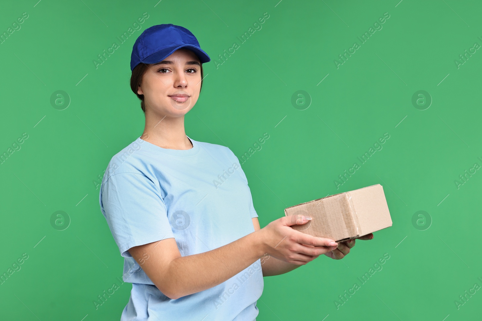 Photo of Girl in uniform with parcel on green background. Work for teenagers