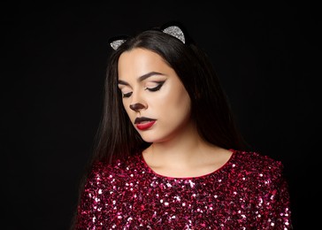 Photo of Charming woman with cat makeup and ears on black background