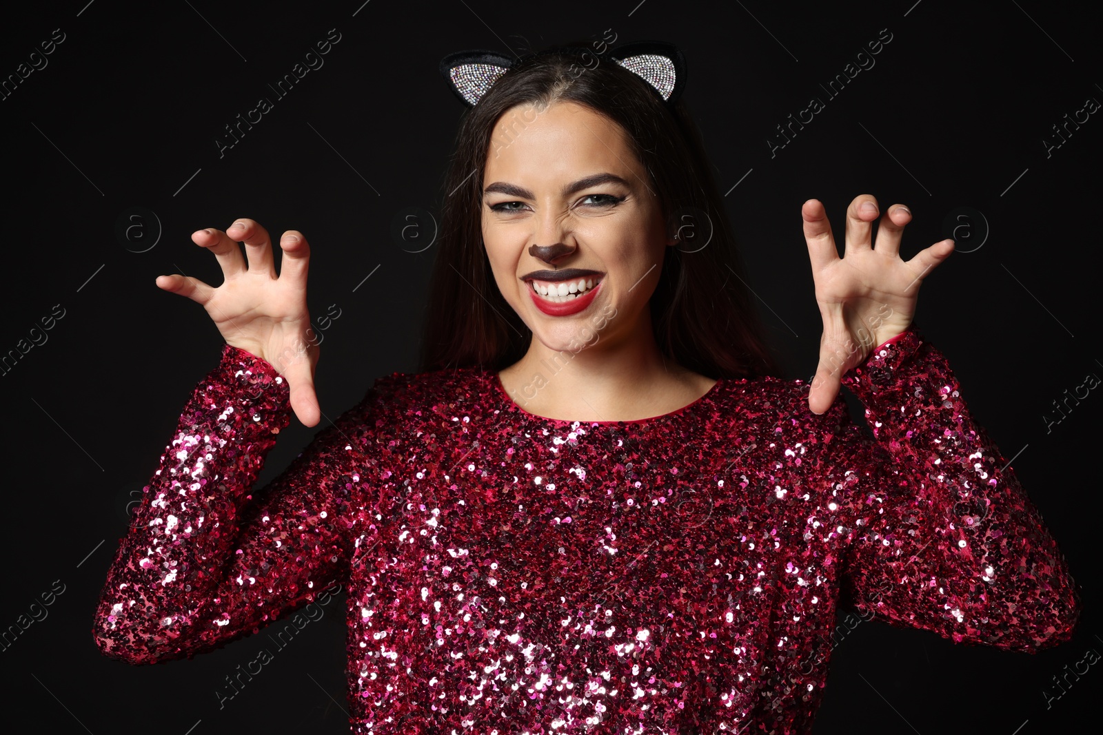 Photo of Playful woman with cat makeup and ears on black background