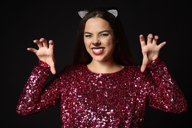 Photo of Playful woman with cat makeup and ears on black background