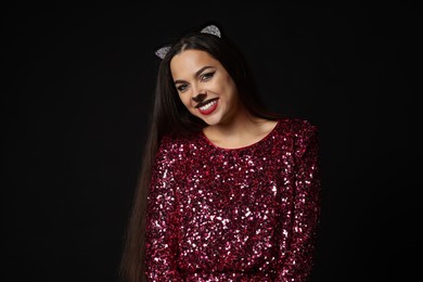 Photo of Charming woman with cat makeup and ears on black background