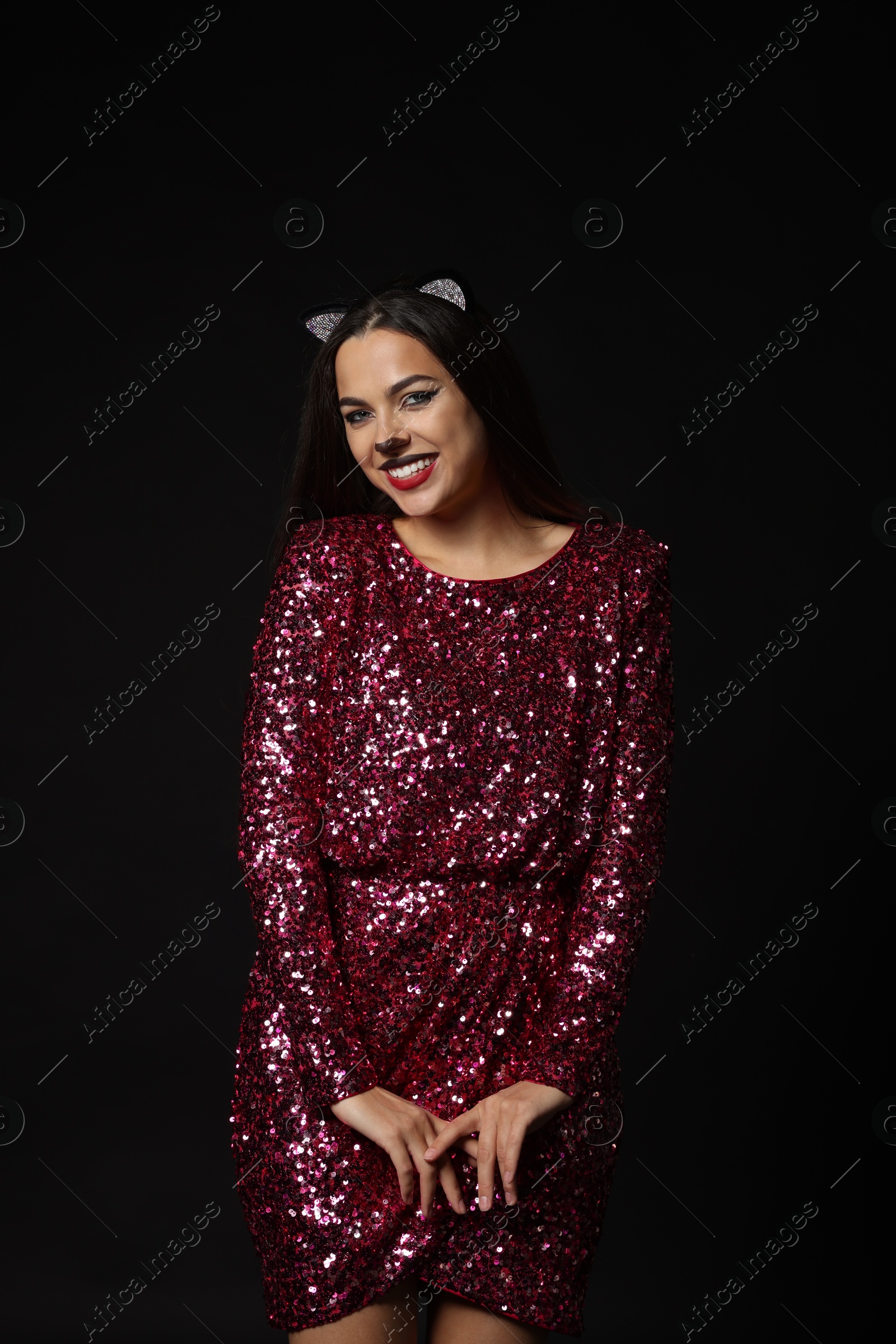 Photo of Charming woman with cat makeup and ears on black background