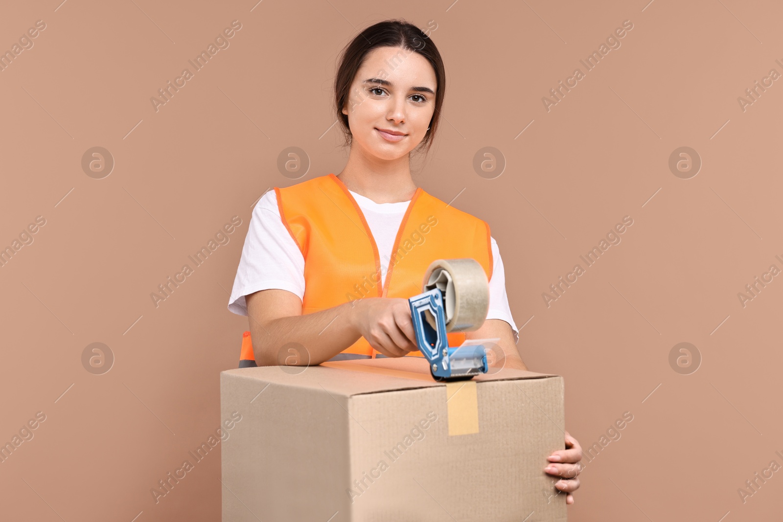 Photo of Girl packing box with adhesive tape on pale brown background. Work for teenagers