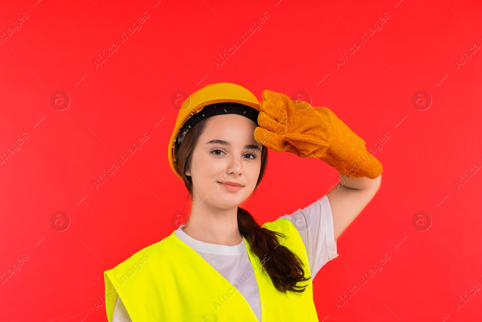 Photo of Girl with safety equipment on red background. Work for teenagers