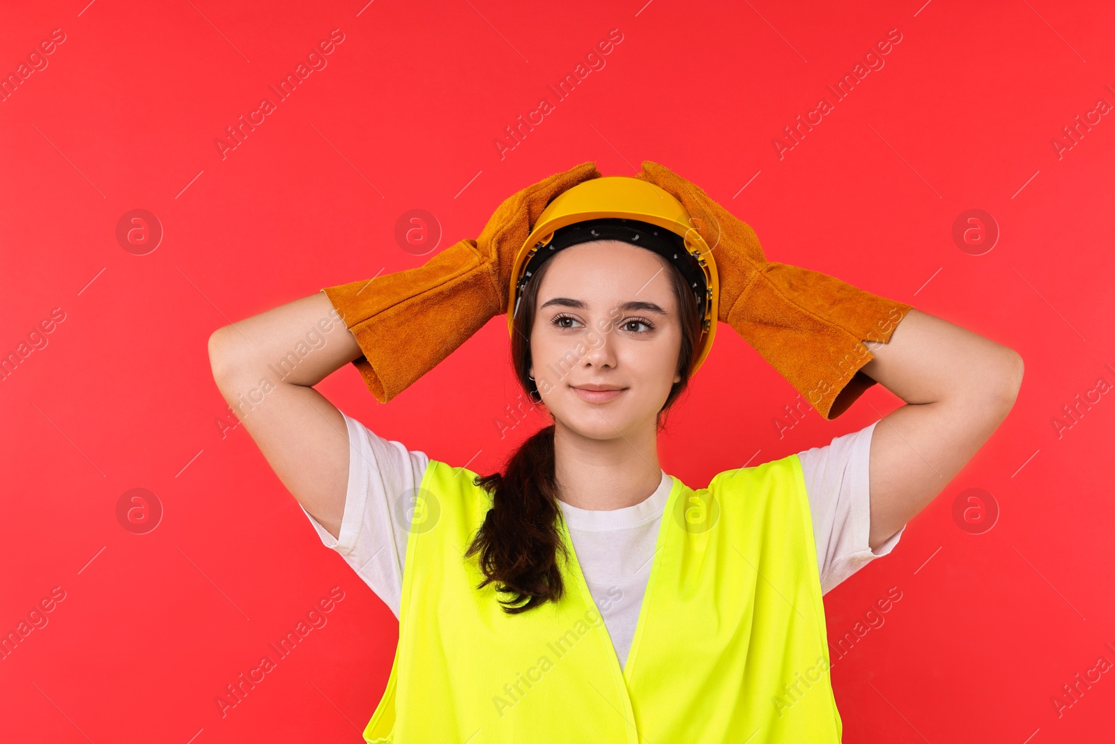 Photo of Girl with safety equipment on red background. Work for teenagers