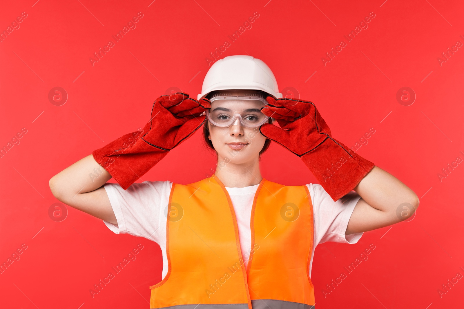 Photo of Girl with safety equipment on red background. Work for teenagers