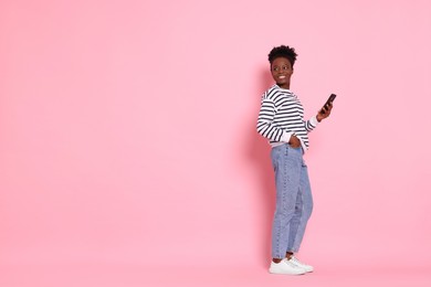 Photo of Happy woman with smartphone on pink background. Space for text