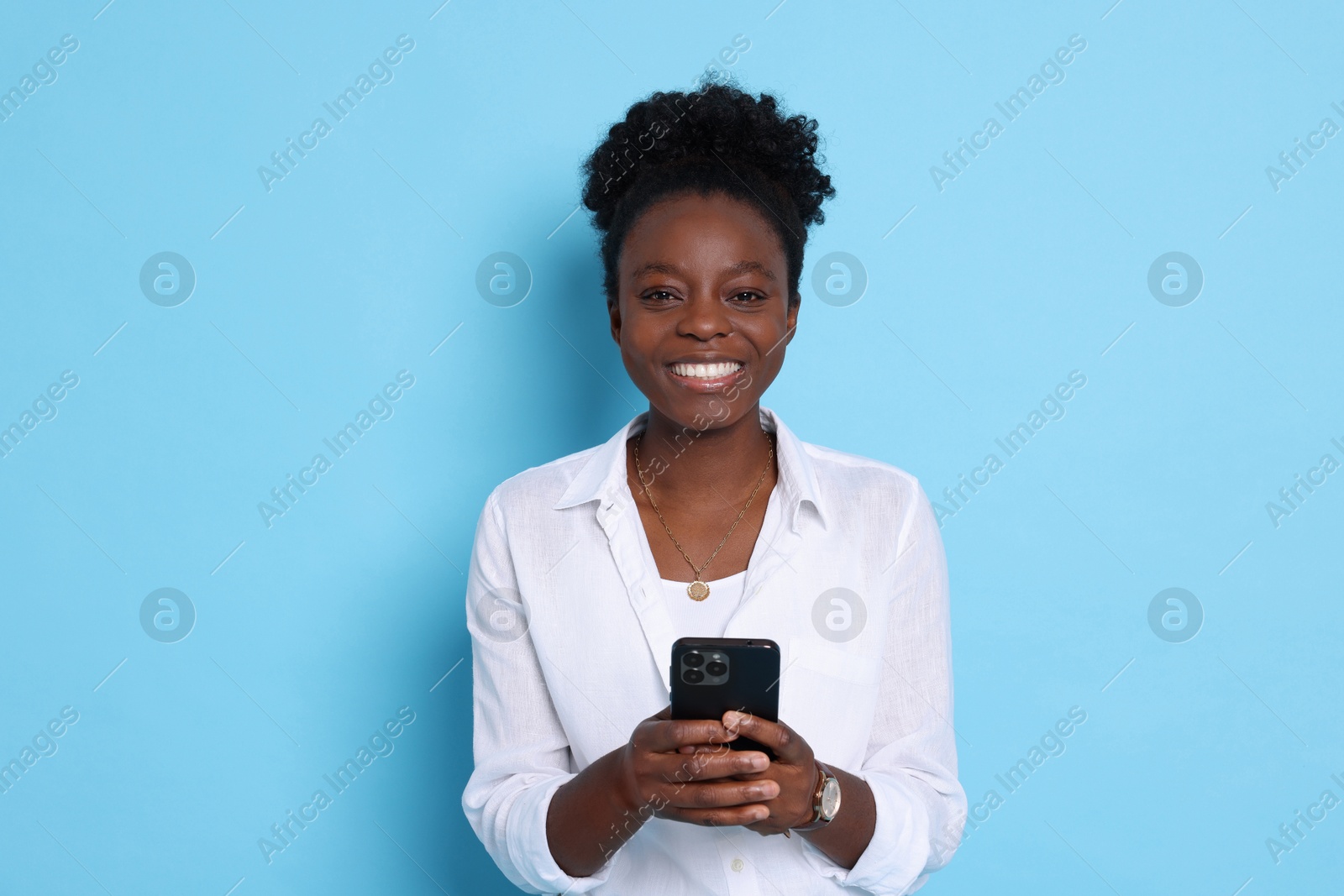 Photo of Happy woman with smartphone on light blue background