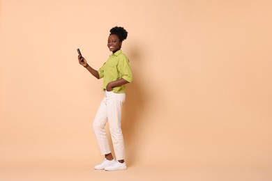 Photo of Happy woman with smartphone on beige background. Space for text