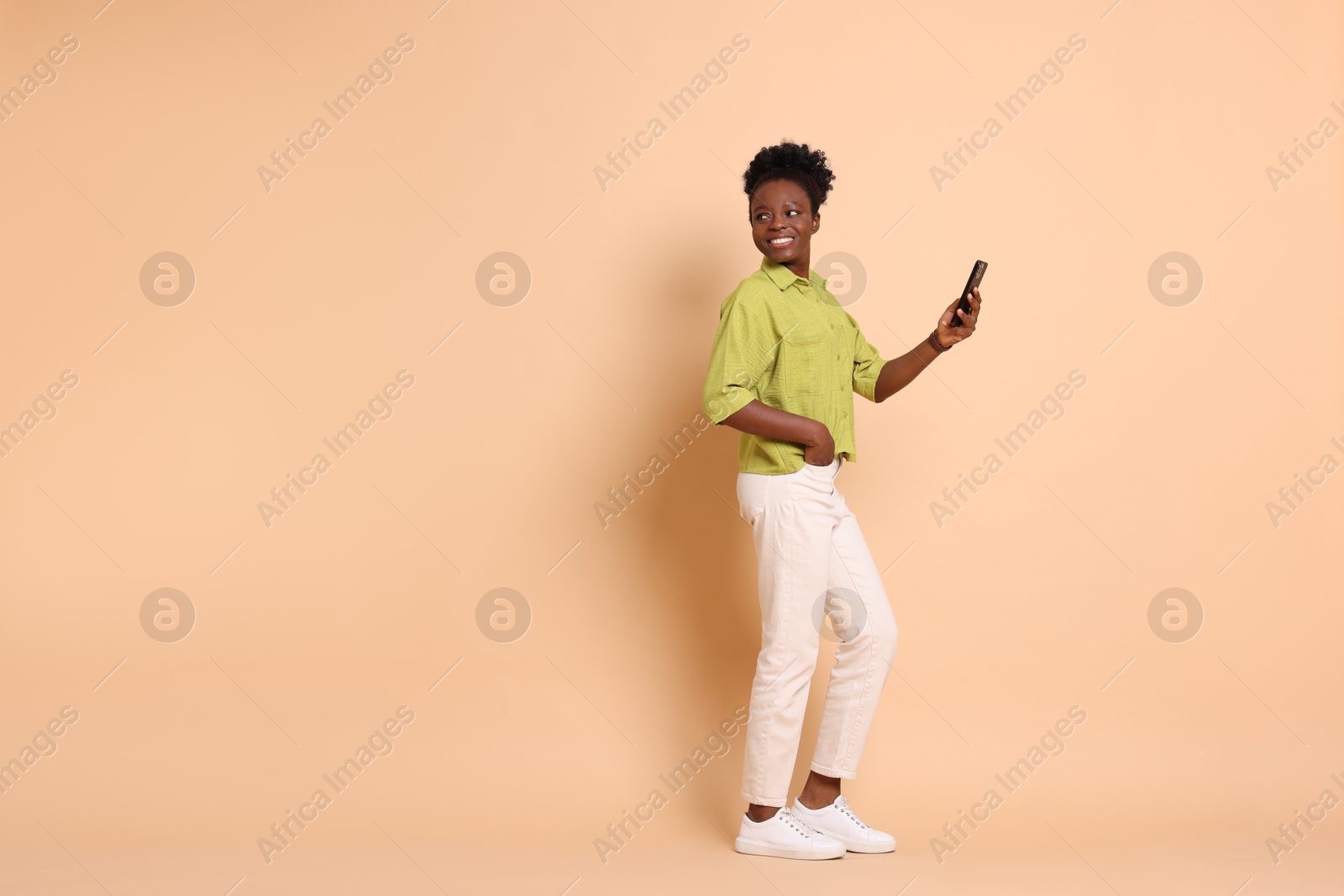 Photo of Happy woman with smartphone on beige background. Space for text