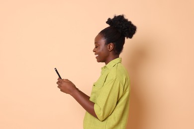 Photo of Happy woman with smartphone on beige background. Space for text