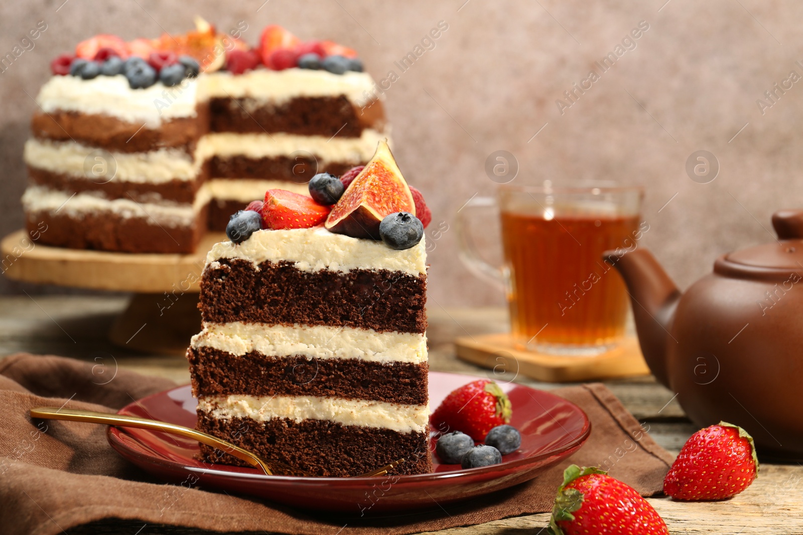 Photo of Piece of delicious chocolate sponge cake with berries served on wooden table