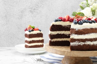 Photo of Delicious chocolate sponge cake with berries served on white table