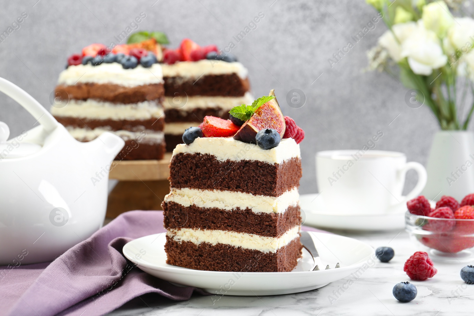 Photo of Piece of delicious chocolate sponge cake with berries served on white table