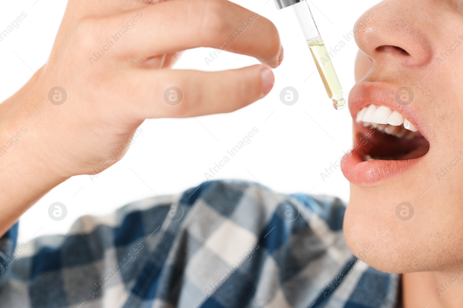 Photo of Young man taking CBD tincture indoors, closeup