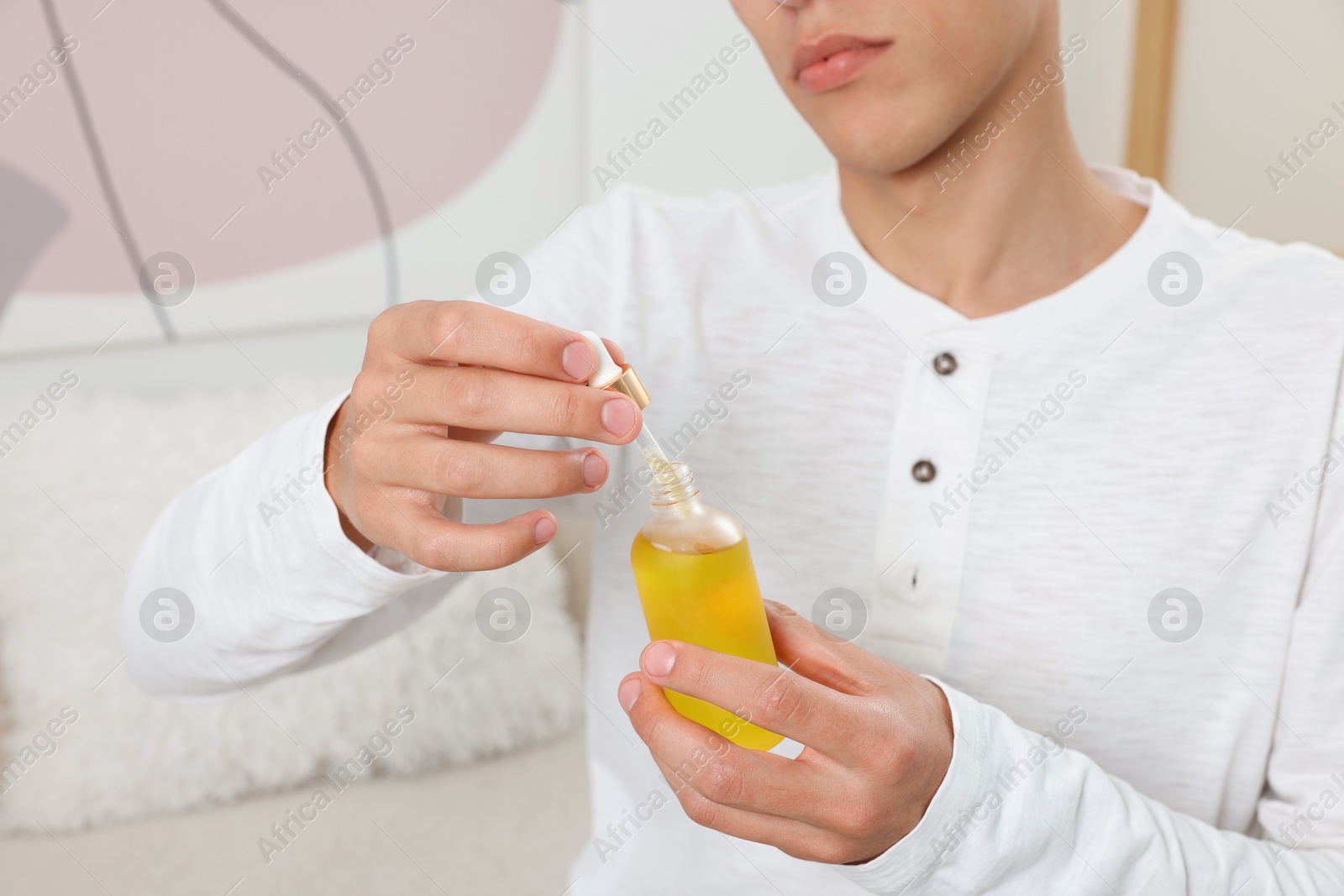 Photo of Young man taking CBD tincture indoors, closeup