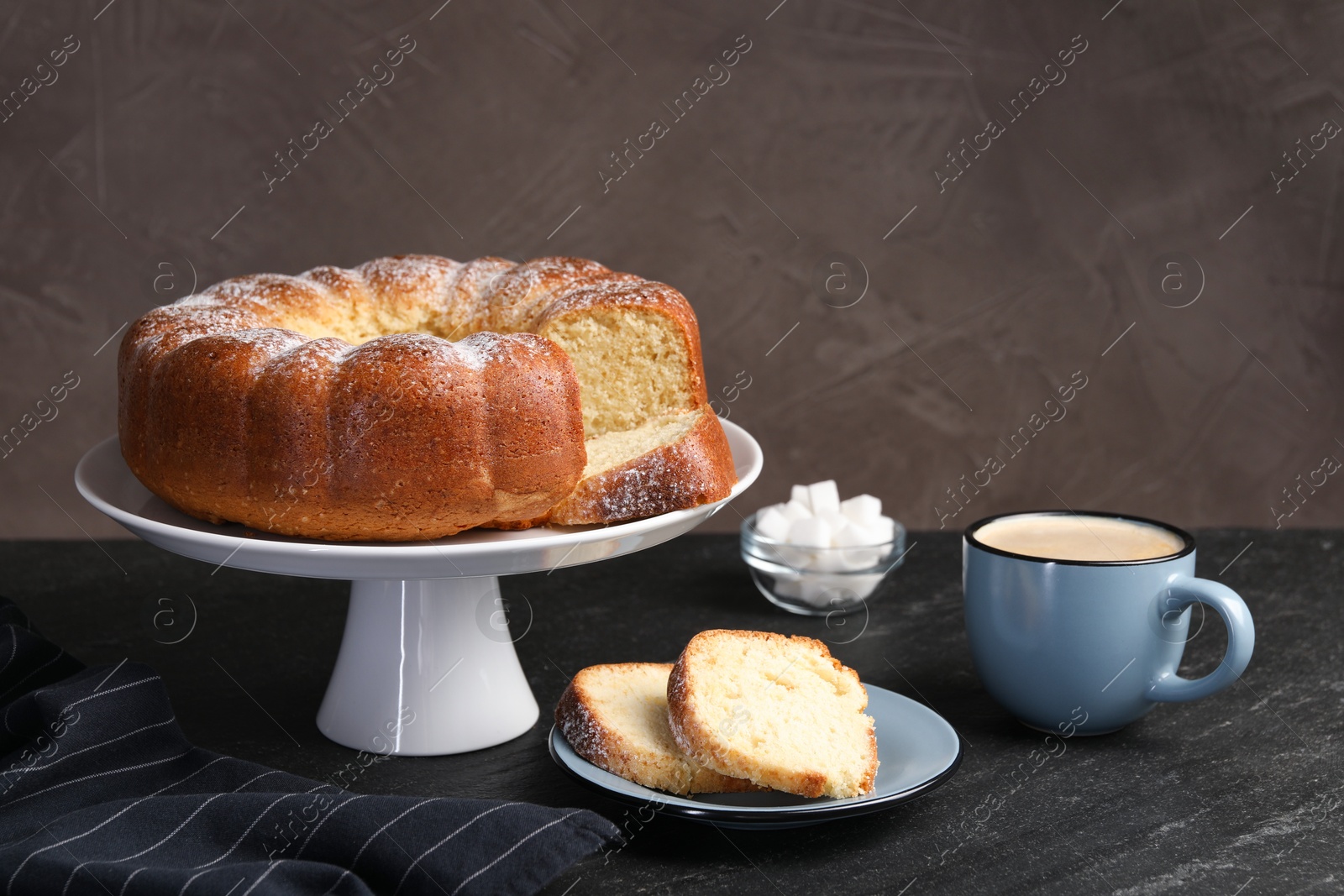 Photo of Freshly baked sponge cake, sugar cubes and coffee on black table