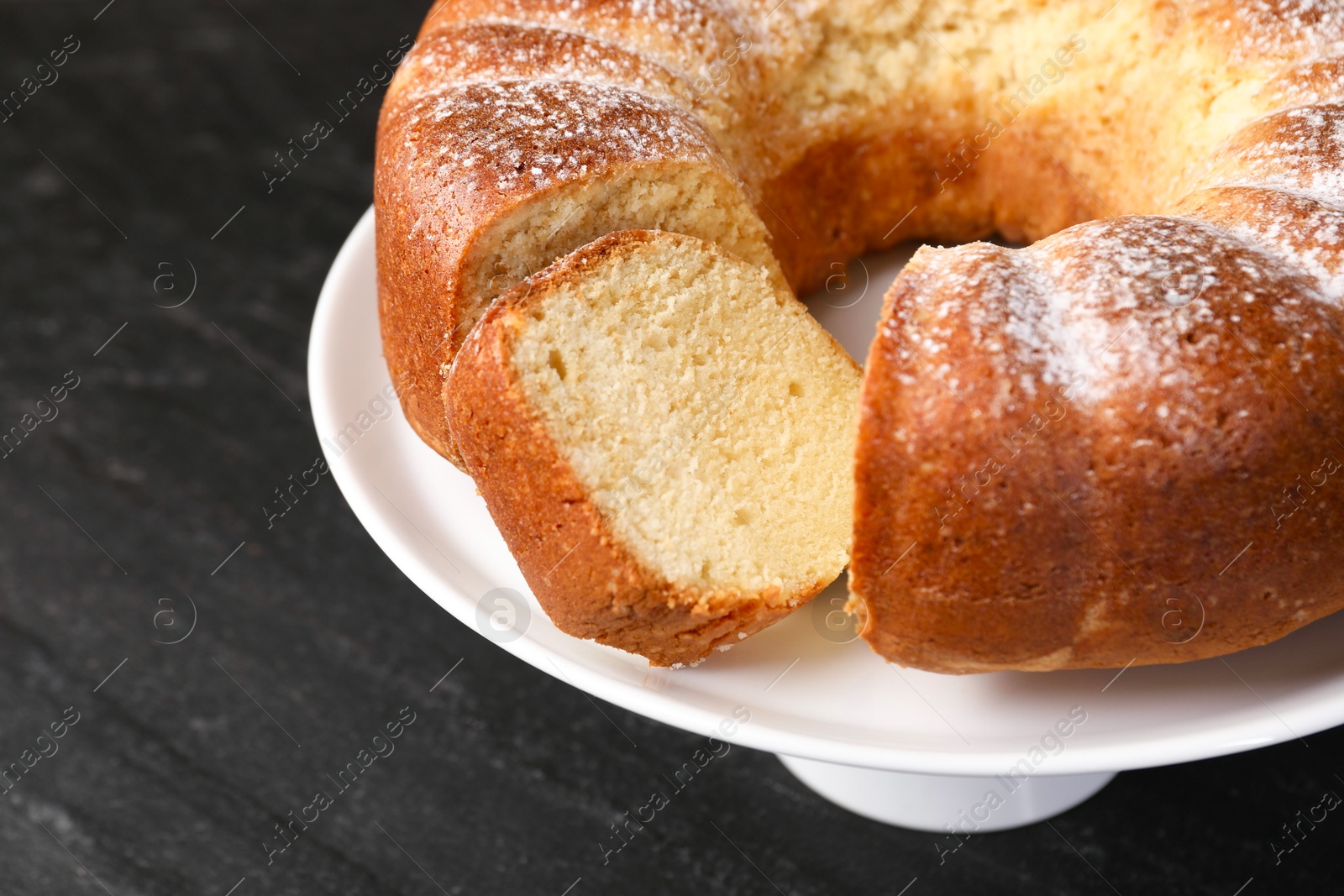 Photo of Freshly baked sponge cake on black table, closeup