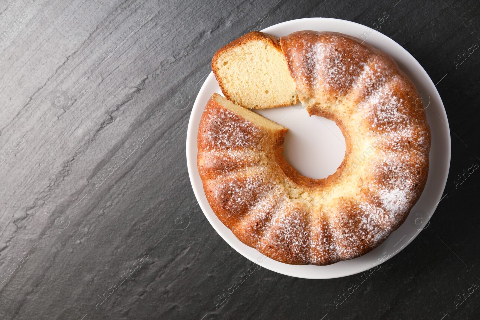 Photo of Freshly baked sponge cake on black table, top view. Space for text