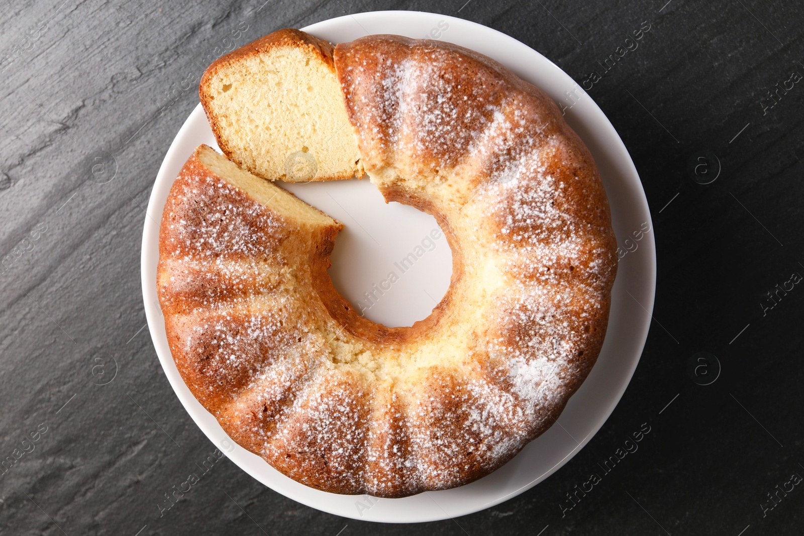 Photo of Freshly baked sponge cake on black table, top view