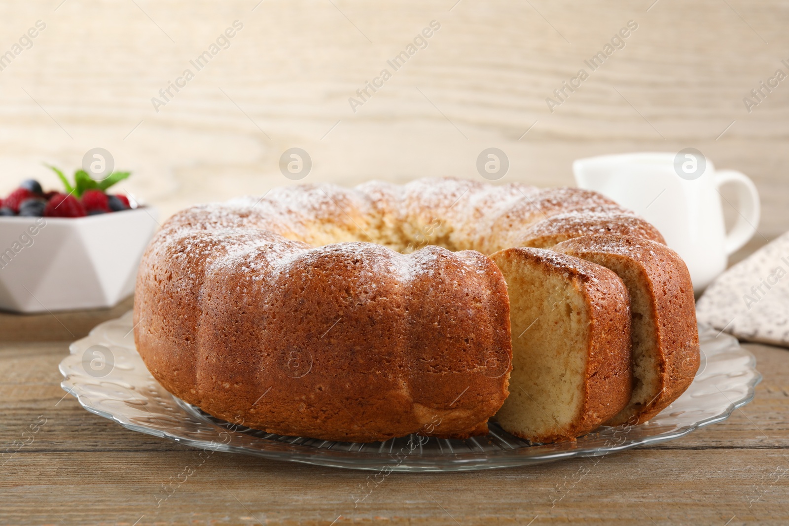 Photo of Freshly baked sponge cake served on wooden table, closeup