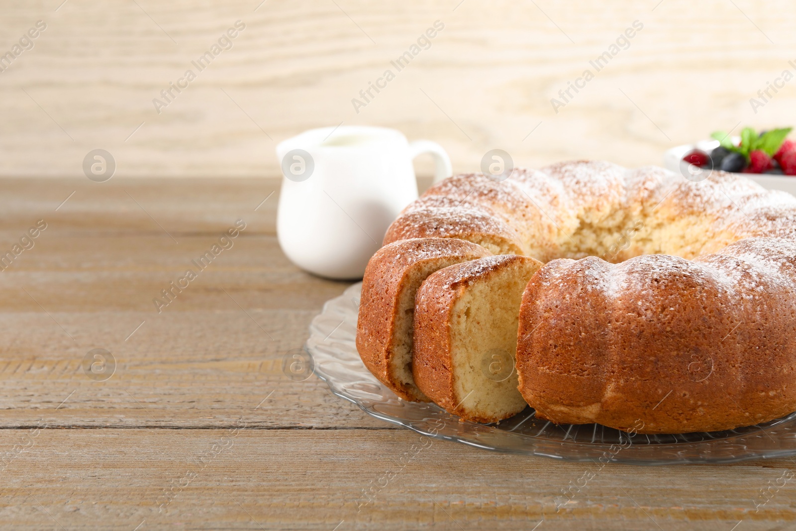 Photo of Freshly baked sponge cake, milk and berries on wooden table, closeup. Space for text