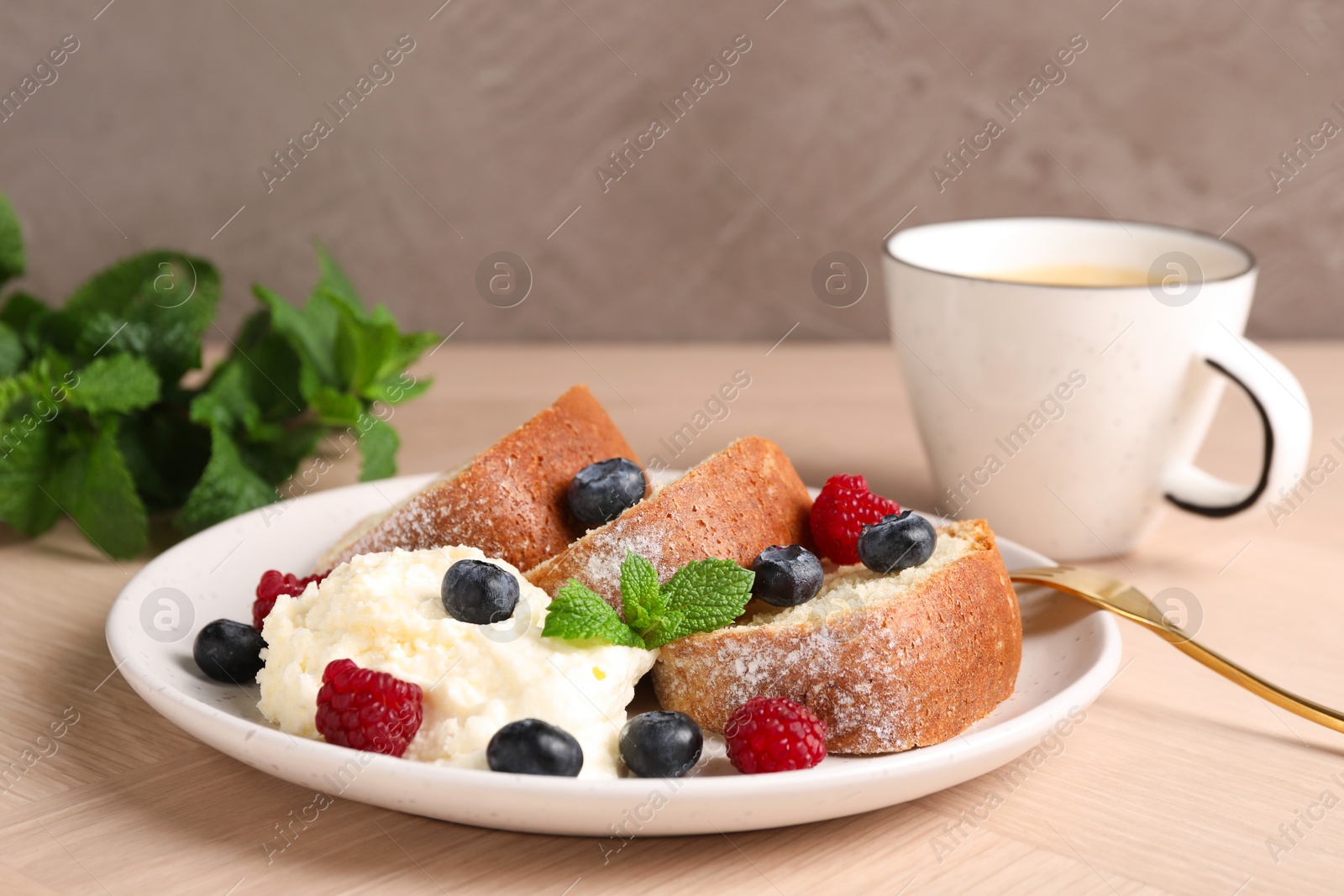 Photo of Pieces of freshly baked sponge cake, berries, ice cream, mint and coffee on wooden table, closeup