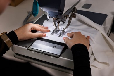 Photo of Woman working with sewing machine in professional workshop, closeup