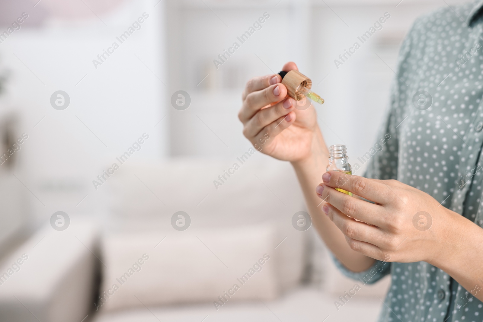 Photo of Young woman taking CBD tincture indoors, closeup. Space for text