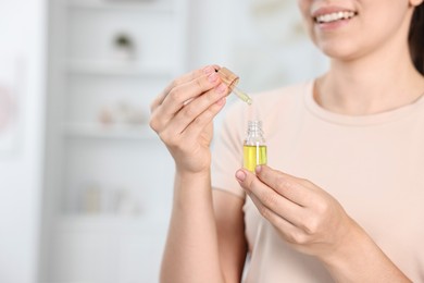 Photo of Young woman taking CBD tincture indoors, closeup. Space for text