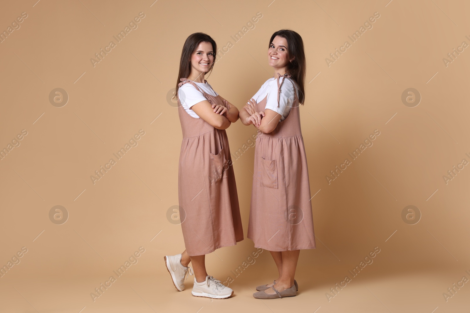 Photo of Portrait of happy twin sisters on pale brown background