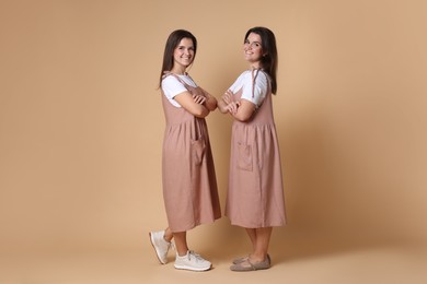 Photo of Portrait of happy twin sisters on pale brown background