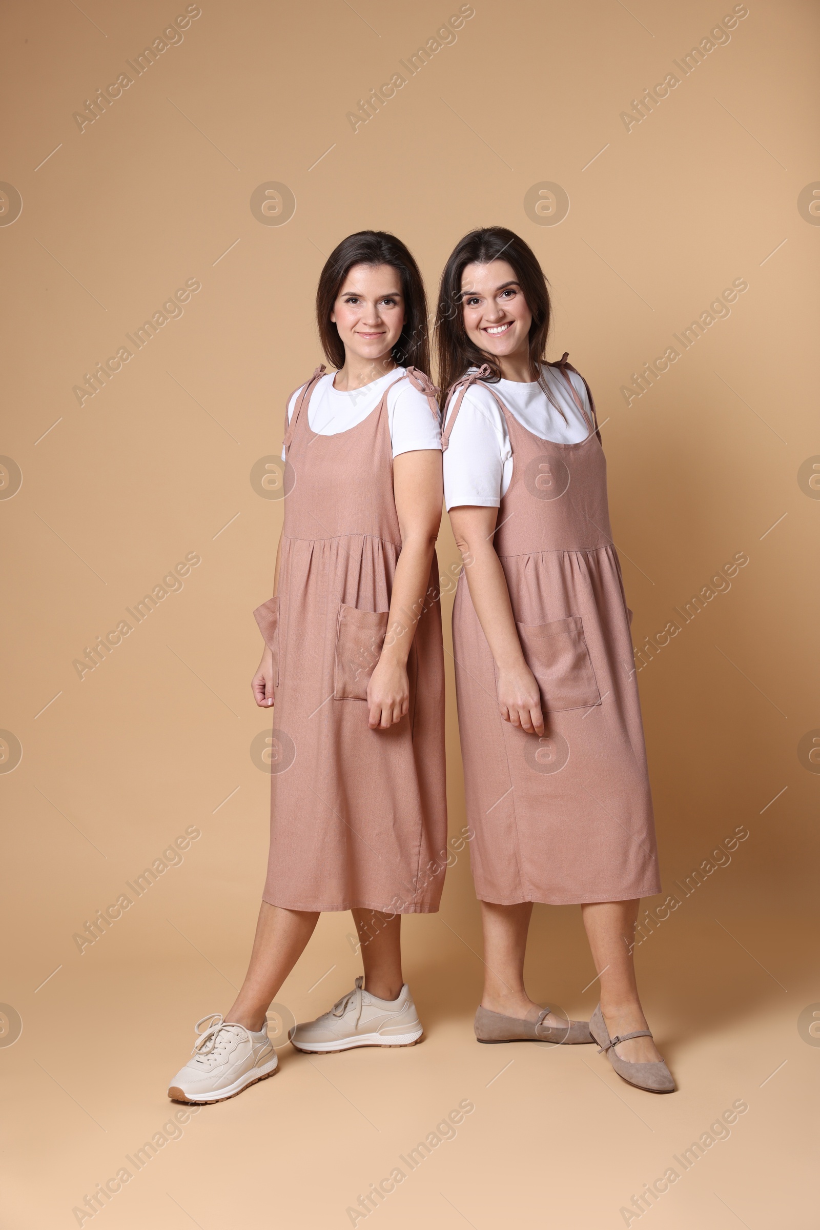 Photo of Portrait of happy twin sisters on pale brown background