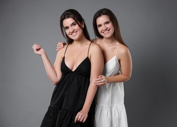 Photo of Portrait of beautiful twin sisters on grey background