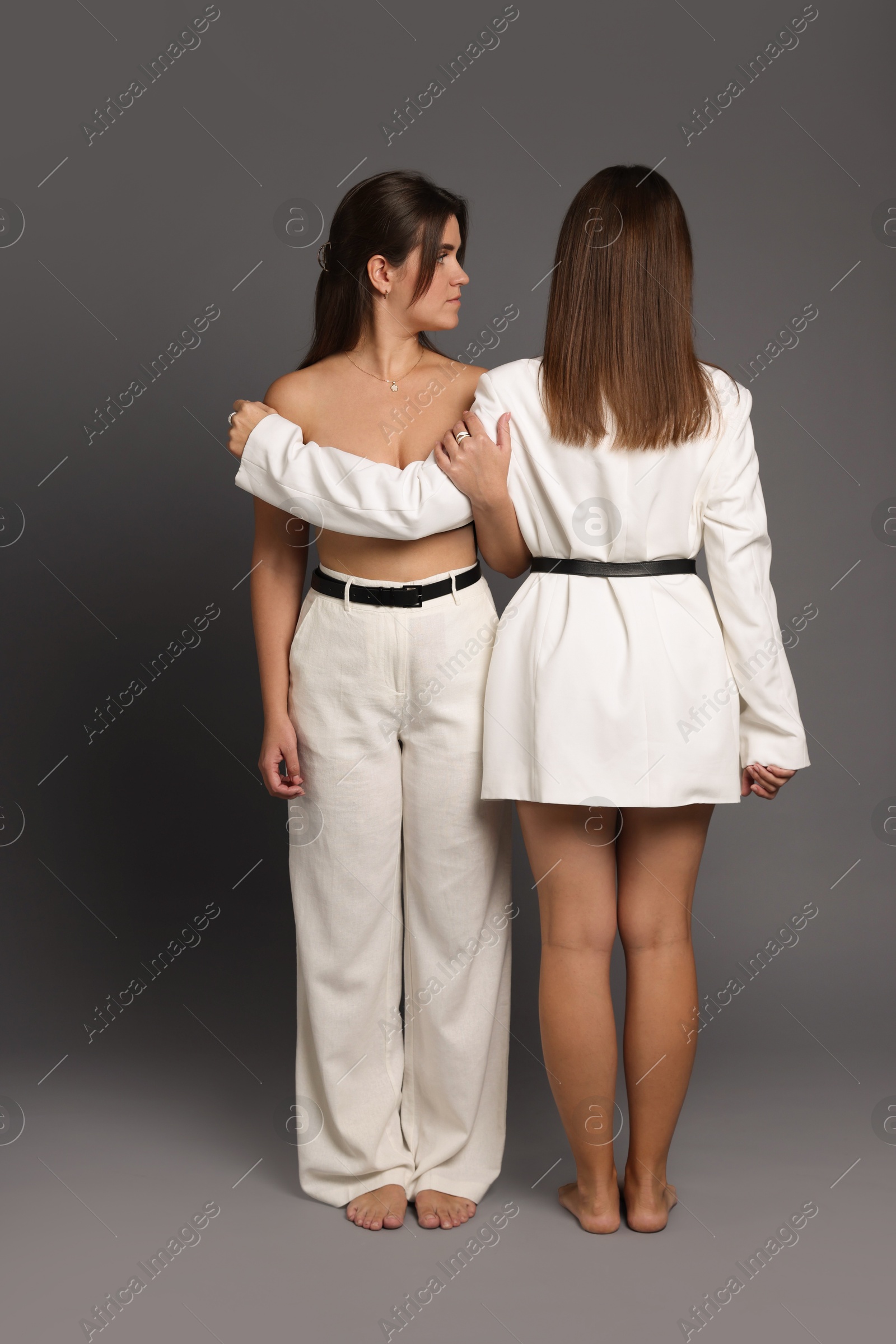 Photo of Portrait of beautiful twin sisters on grey background