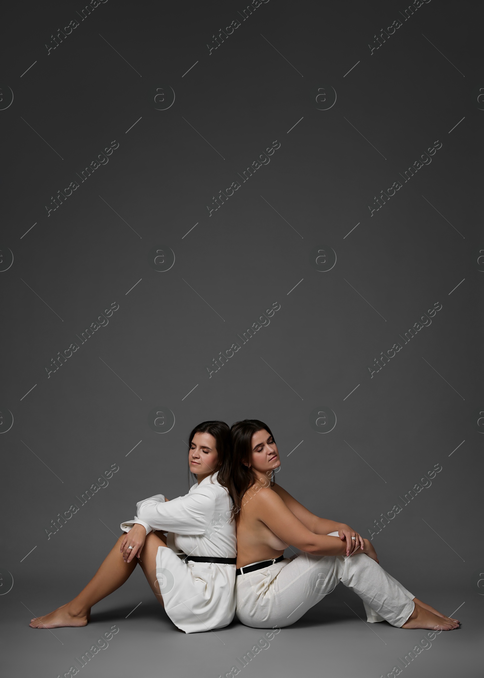 Photo of Portrait of beautiful twin sisters on grey background